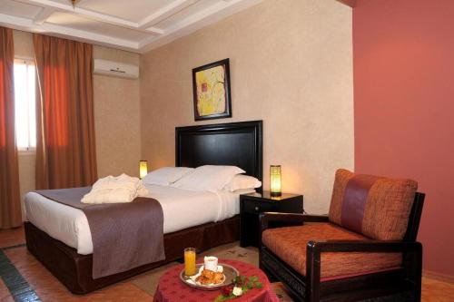 une chambre d'hôtel avec un lit et une chaise dans l'établissement Art suites, à El Jadida