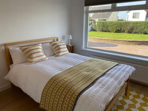 una camera da letto con un letto e una grande finestra di Modern holiday home with sea view- close to beach a Portstewart