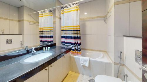 a bathroom with a sink and a tub at Hometown Apartments - Waterfront 1 Bedroom apartment in Westside Marina in Dubai