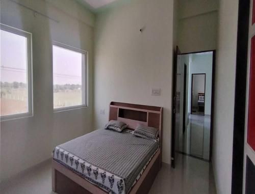 a bedroom with a bed and two windows at HOTEL HOLIDAY HOME, DAUSA in Dausa