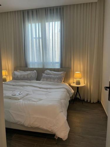 Un dormitorio con una gran cama blanca y una ventana en Smart Entry Apartment en Riad