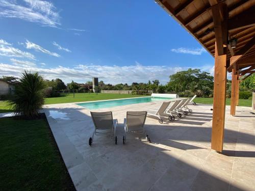 un grupo de sillas sentadas junto a una piscina en Large House near Marciac & Heated Salt Water Pool, en Plaisance