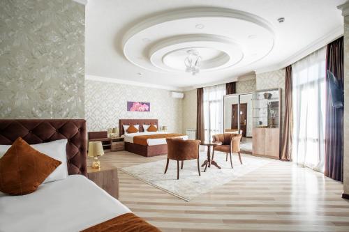 Manifa Hotel في طشقند: غرفة فندقية بسرير وطاولة وكراسي