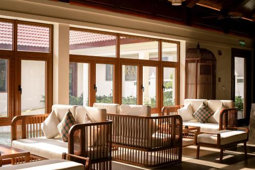 una sala de estar con sofás blancos y ventanas en Senna Wellness Retreat en Bắc Ninh