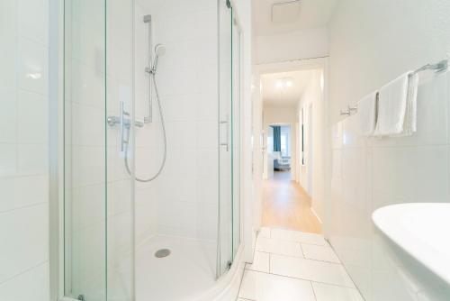 uma casa de banho branca com um chuveiro e um lavatório. em Tanneneck Wohnung 2 em Travemünde
