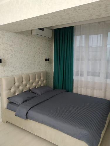 a bedroom with a large bed with a green curtain at Молодежный in Almaty