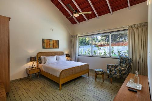 カルジャットにあるSaffronStays Mariposa by the River Montana, Karjatのベッドと椅子と窓のある寝室