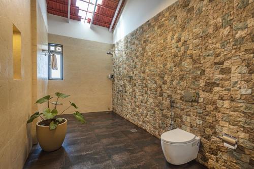 カルジャットにあるSaffronStays Mariposa by the River Montana, Karjatのトイレとレンガの壁があるバスルーム