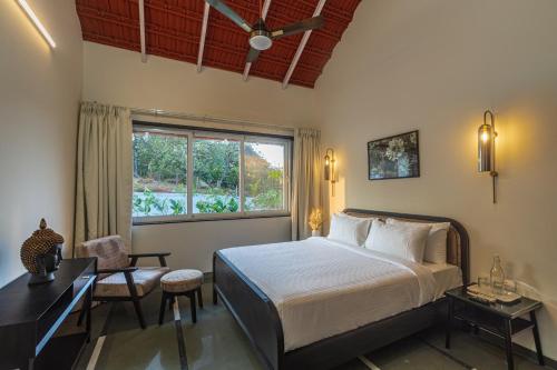 a bedroom with a bed and a desk and a window at SaffronStays Mariposa by the River Rio, Karjat in Karjat