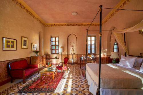 a bedroom with a bed and a chair and a table at Al Moudira Hotel in Luxor