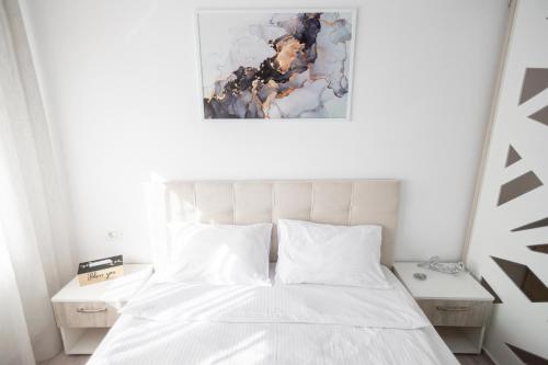 een slaapkamer met een wit bed en een schilderij aan de muur bij White home in Timişoara