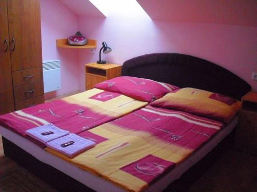 a bedroom with a bed with pink sheets and pink pillows at Penzion u Balcarky in Ostrov u Macochy