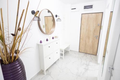 een badkamer met een spiegel en een vaas met een plant bij White home in Timişoara
