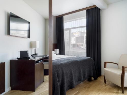 a bedroom with a bed and a desk and a window at Hotel Kea by Keahotels in Akureyri
