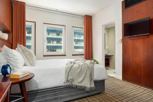 a bedroom with a white bed and a television at Neighbourgood East City in Cape Town