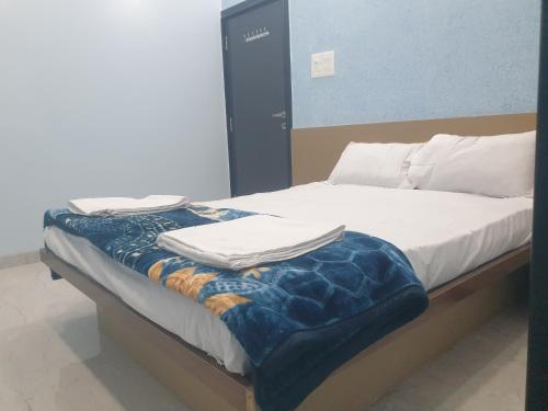 a bed with white sheets and a blue blanket on it at Hotel Taj Bi Plaza in Aurangabad
