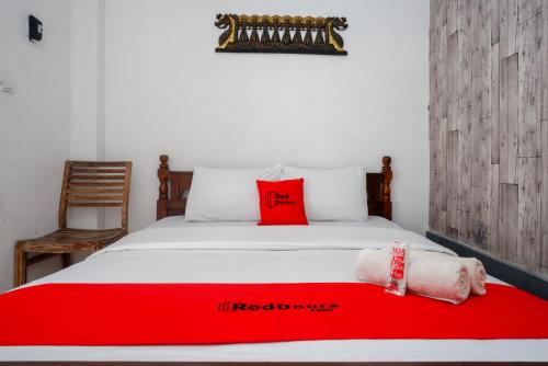 a bed with red pillows and a red blanket at RedDoorz Syariah near Plengkung Gading 2 in Yogyakarta