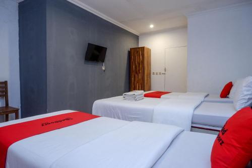 a hotel room with three beds and a television at RedDoorz Syariah near Plengkung Gading 2 in Yogyakarta