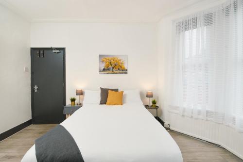 een slaapkamer met een groot wit bed en een raam bij LARGE GROUPS- 5 bed House in Harringay in Londen