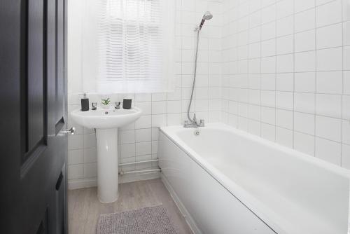 y baño blanco con lavabo, bañera y lavamanos. en LARGE GROUPS- 5 bed House in Harringay, en Londres