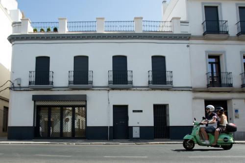 twee mensen op een scooter voor een gebouw bij Casas de Sevilla - Apartamento A Pie de Muralla - Centro Histórico in Sevilla