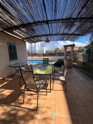 a patio with a table and chairs under a pergola at Chalet con piscina Sa Ràpita in Sa Ràpita