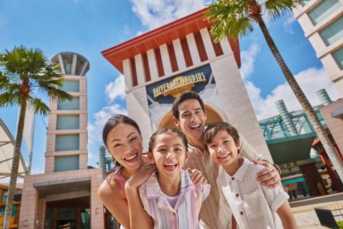 a family posing in front of the mickey mouse sign at the disney world at Resorts World Sentosa - Hotel Michael in Singapore