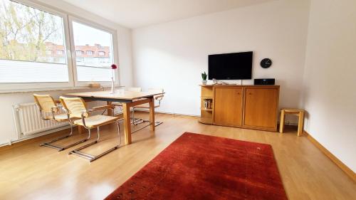 uma sala de estar com uma mesa e cadeiras e uma televisão em Deine Oase mitten in Hannover. em Hanôver