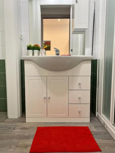 ein Badezimmer mit Waschbecken und einem roten Teppich in der Unterkunft Bnbook Monolocale Gandhi in Rho