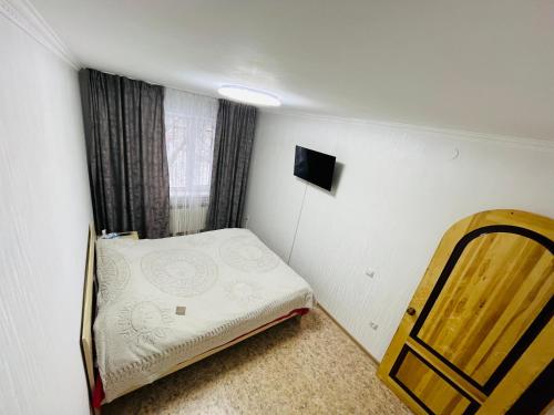 a small bedroom with a bed and a window at Апартаменты Ермекова 23 in Karagandy