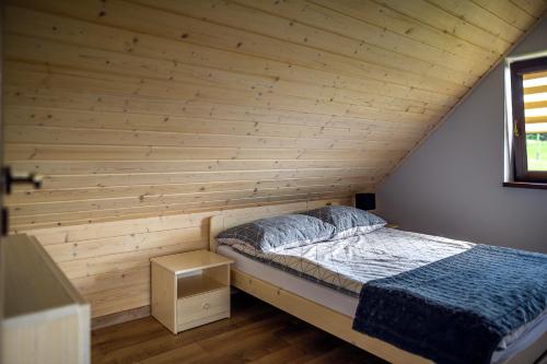 a bed in a room with a wooden wall at Domek w Klisiówkach in Ujsoły