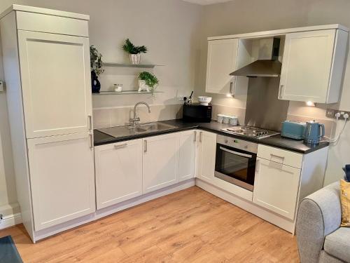 una cucina con mobili bianchi e un lavandino di Russets Rest a York