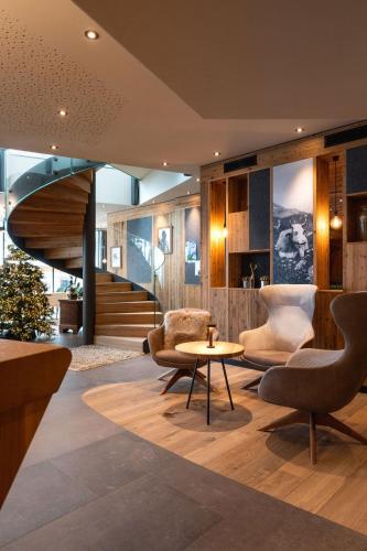 a lobby with chairs and a table and a staircase at Hotel Sun Valley in Selva di Val Gardena