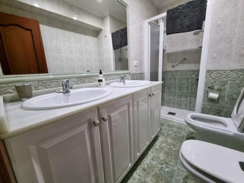 een badkamer met 2 wastafels, een toilet en een spiegel bij 126B Apto Playa - 3 Habitaciones in Gijón