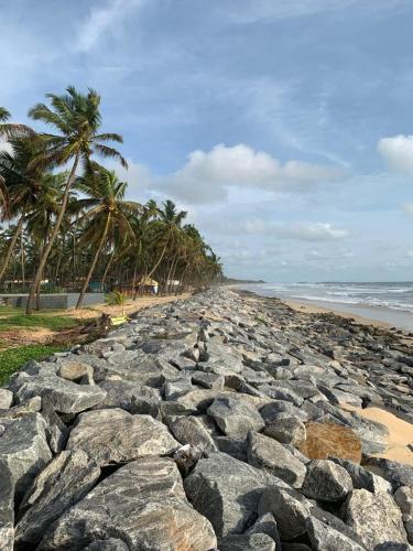 a large group of rocks on a beach with palm trees at Delta Hospitality - Sea facing rooms with a PRIVATE BEACH in Kalyānpur