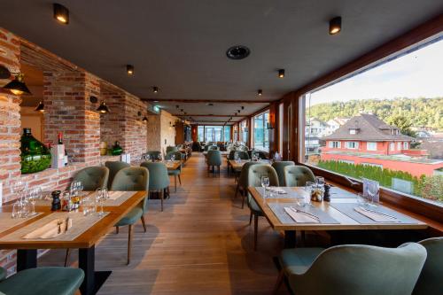 un restaurante con mesas y sillas de madera y ventanas grandes en Welcome Apartments Spiez en Spiez