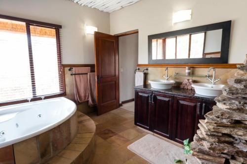 a bathroom with two sinks and a tub at The Citrine House 33 in Mabula