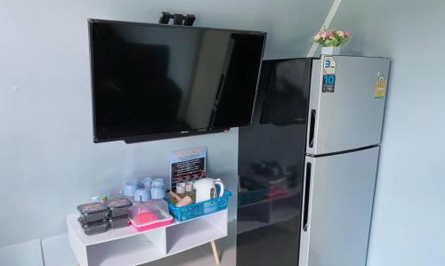 a flat screen tv hanging above a refrigerator at บ้าน วังน้ำเขียว in Ban Kom