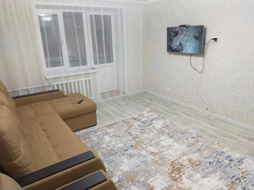 ein Wohnzimmer mit einem Sofa und einem Fenster in der Unterkunft Отличная 3х комнатная квартира in Oral