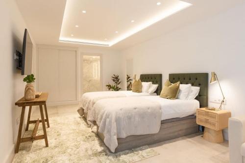 a white bedroom with two beds and a table at BAMANIJA by Buenavilla in Puerto Calero