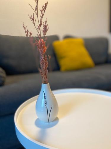 a white vase with flowers in it on a table at Art Apart Nomay Summercard Blick Top of Salzburg in Kaprun