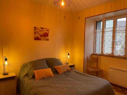 ein Schlafzimmer mit einem Bett mit orangefarbenen Wänden und einem Fenster in der Unterkunft Gîte du Morvan in Saint-Germain-des-Champs