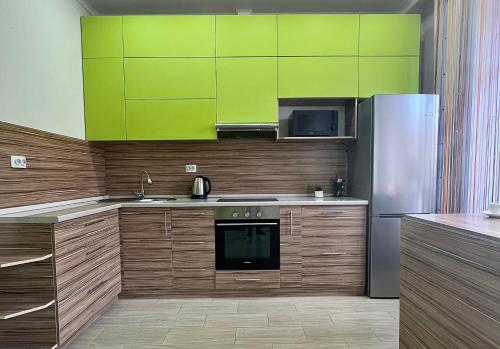 a kitchen with wooden cabinets and a stainless steel refrigerator at Апартаменты в новом ЖК in Pavlodar