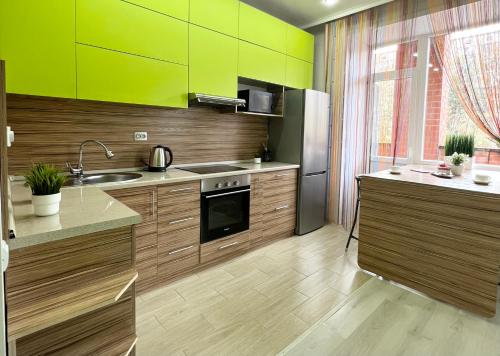 a kitchen with wooden cabinets and a green wall at Апартаменты в новом ЖК in Pavlodar