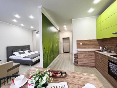 a bedroom with a bed and a kitchen with a table at Апартаменты в новом ЖК in Pavlodar