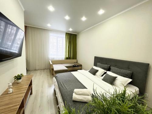 una camera con un grande letto e un divano di Апартаменты в новом ЖК a Pavlodar