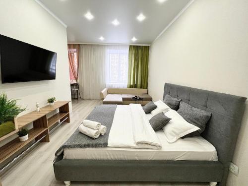 a bedroom with a large bed and a flat screen tv at Апартаменты в новом ЖК in Pavlodar