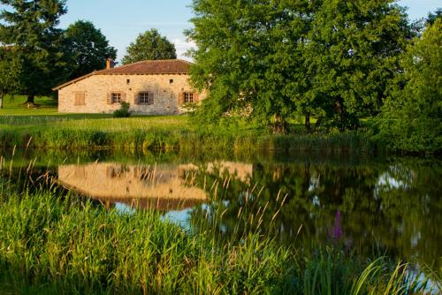an old house is reflected in the water of a lake at HOTEL Domaine des Etangs, Auberges Resorts Collection in Massignac