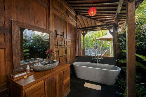 ein Badezimmer mit Badewanne und Waschbecken in der Unterkunft Kawan Antique Ubud Villa in Ubud