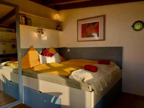 a bedroom with a large bed with yellow and red pillows at Tiny House Vogelnest in Puntagorda